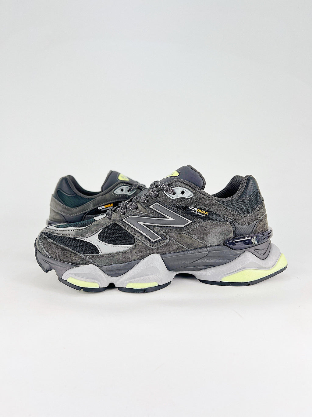 New Balance 9060 sneakers shown are in a black and cement colorway, often featuring a durable mesh and suede construction with Lime accents