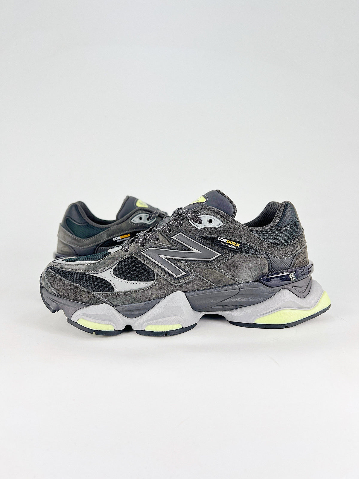 New Balance 9060 sneakers shown are in a black and cement colorway, often featuring a durable mesh and suede construction with Lime accents