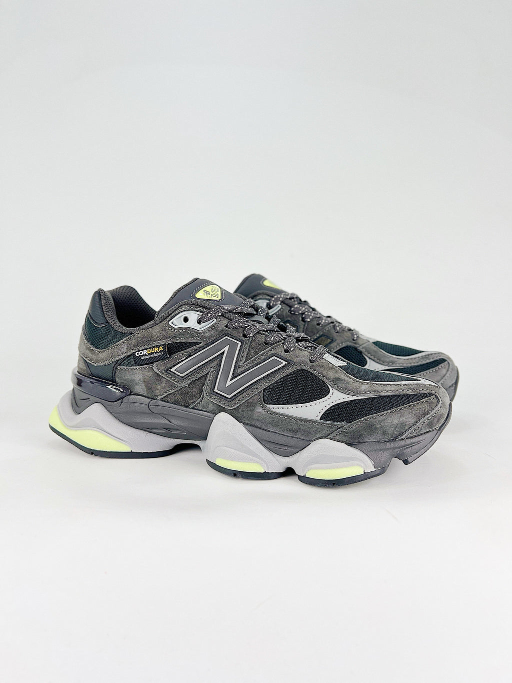 New Balance 9060 sneakers shown are in a black and cement colorway, often featuring a durable mesh and suede construction with Lime accents
