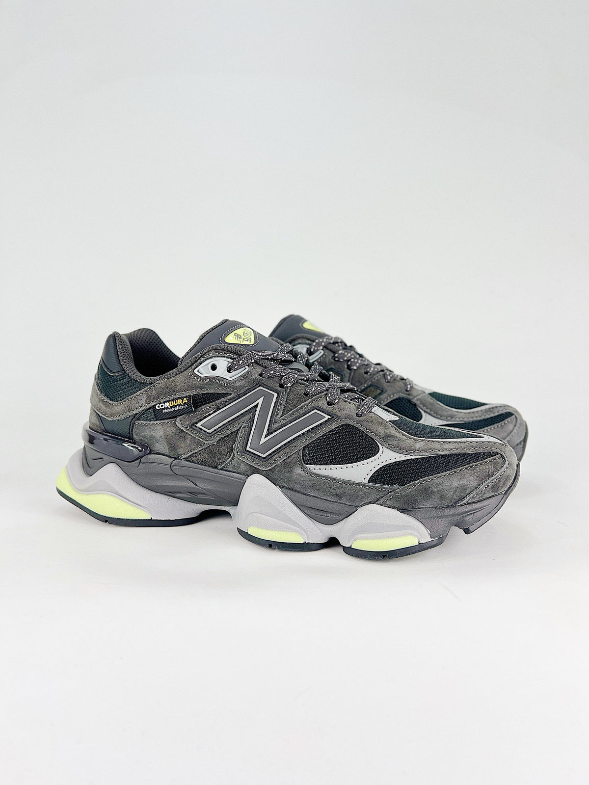 New Balance 9060 sneakers shown are in a black and cement colorway, often featuring a durable mesh and suede construction with Lime accents