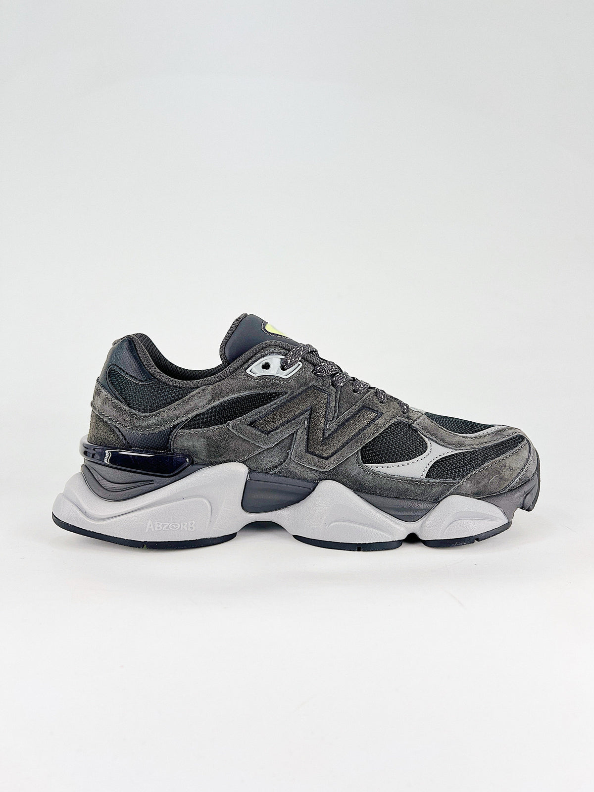 New Balance 9060 sneakers shown are in a black and cement colorway, often featuring a durable mesh and suede construction with Lime accents